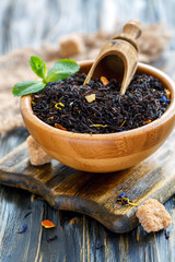 Black tea with bergamot and scoop in a wooden bowl.