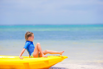 Adorable little girl kayaking on the beach vacation