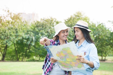 Women traveler with backpack checks map to find directions in the park of Thailand,active people lifestyle