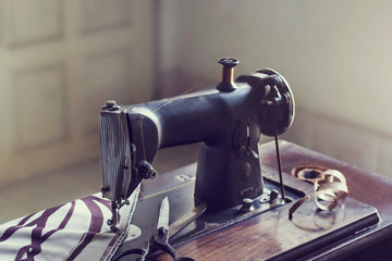 vintage sewing machine with fabric and scissor in the room
