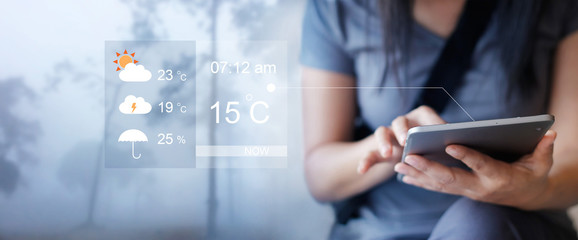 Woman checking up the weather forecast from tablet application