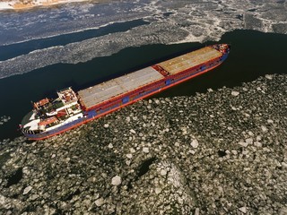 Cargo ship on the ice river in winter. Aerial view. © kolidzei