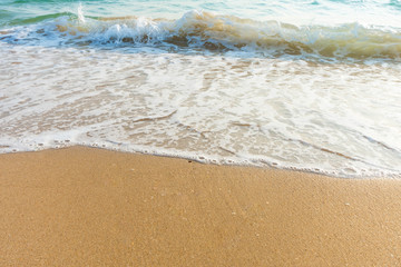 Soft wave of blue ocean on sandy beach at sunny day. Background subject is soft focus