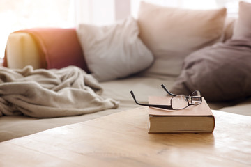 book with eyeglasses on table in front of couch