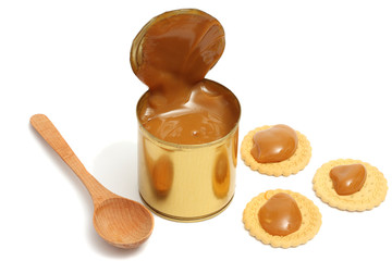 Condensed milk with wood spoon isolated on white background