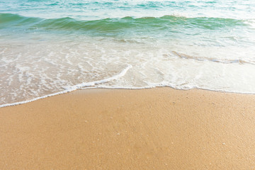 Soft wave of blue ocean on sandy beach at sunny day. Background subject is soft focus