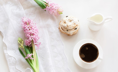 Morning romance breakfast, cup of coffee, milk jug and cake with decor of pink hyacinth. Spring concept. Top view.