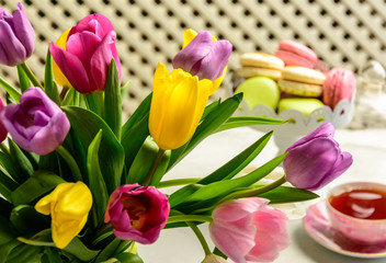 Beautiful festive bouquet of tulips and cakes on white background