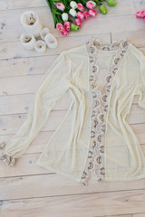 Women's beige dressing gown on a wooden floor with candles and tulips