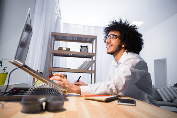 Low view of hipster freelance man using laptop computer and editing board for improving photos or...