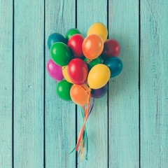 Naklejka premium Colorful bunch of Easter egg balloons on blue wooden background. Minimal creative concept. Flat lay.