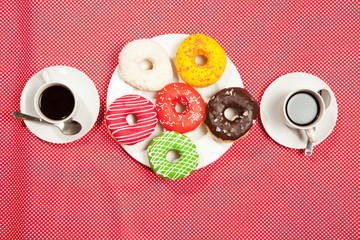 Two cups with coffee and donuts on a red background