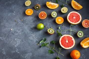 Colorful fresh fruit on dark background. Orange, tangerine, lime, kiwi, grapefruit. Fruit background. Summer food concept. Top view, copy space