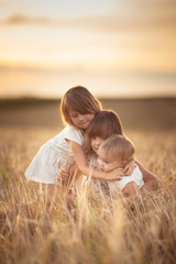 Three girls sisters walk in field with rye sunset