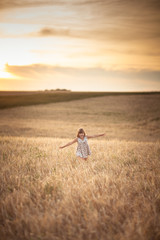 Naklejka na ściany i meble Girl walks in field with rye at sunset, lifestyle
