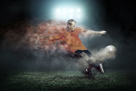 Fototapeta Football player with ball around splash drops on the stadium fie