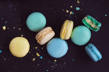 Macaroons on dark background, colorful french cookies macarons. The broken macarons with crumbs