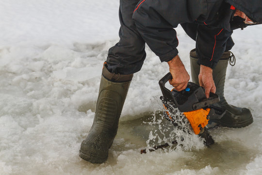 Man Cutting Chainsaw Shell In Ice