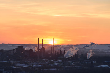 The pipes of the plant throw out toxic smoke at sunset. The sky is red.
