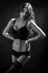 Fototapeta premium beautiful woman show her slim body on black background, monochrome