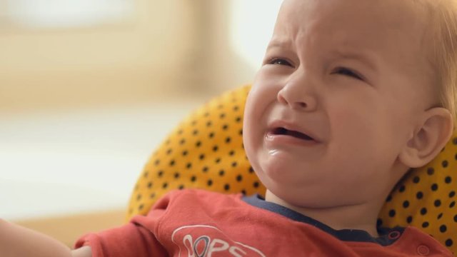 Little baby cries sitting on a chair