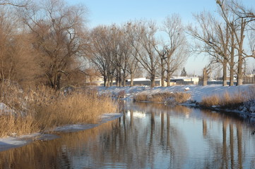 River landscape in winter: trees, snow and water.