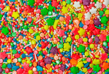 Fototapeta na wymiar Sweet sugar spreading pastry decoration. Сlose view of colorful candy sprinkles.
