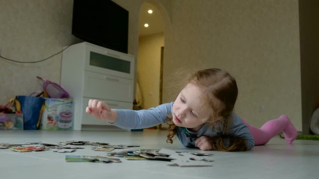 Little cute girls playing puzzles lying on the floor