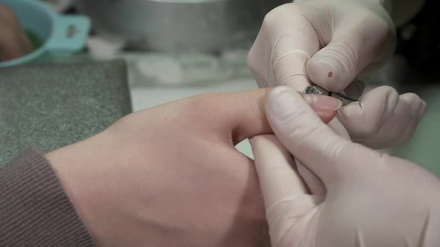 Closeup of manicure master cutting the cuticula on thumb nail