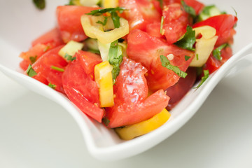 Mixed vegetable salad in a white bowl on white background