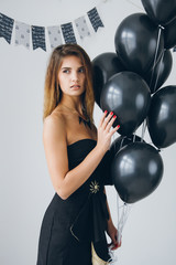 Girl in a black dress with black balloons