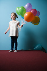 Young girl holds bunch of colorful balloons