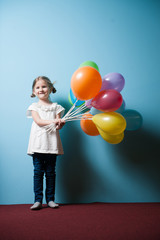 Young girl holds bunch of colorful balloons