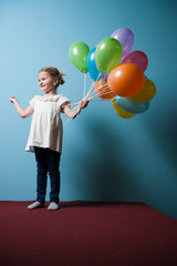 Young girl holds bunch of colorful balloons