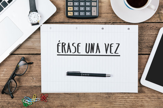 Erase una vez, Spanish text for Once Upon a Time on note pad at office desk with computer technology, high angle