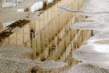 Rainy day. Reflection in puddle on the city street during rain.