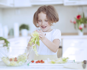 Young girl placing lettuce in salad bowl