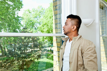 Fototapeta premium Young Indian man looking out window