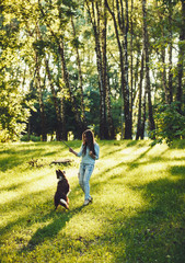 Fototapeta premium Young woman playing with her dog in autumn park.