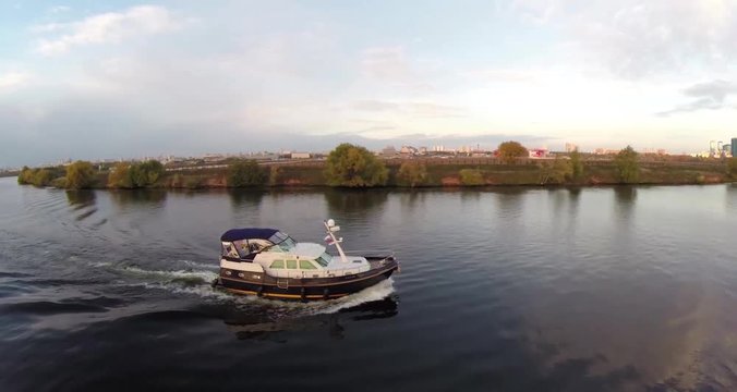Aerial shots of pleasure boat on the Moskva River at Strogino district of Moscow, Russia. Boat navigate on the Moscow river. Sunrise sunset. Alie parusa buildings