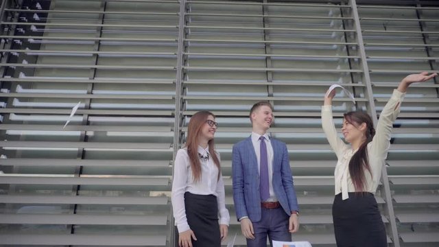 Two Women and One Men Scatter Paper and Rejoice Implementation of Annual of Business Plan and Standing of Business Center Outdoors in Neutral Colors.