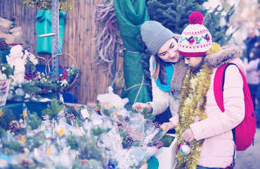 Woman with daughter looking at floral decoration at Cristmas fair