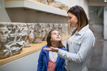 Fototapeta premium Ordinary mother and daughter looking at statues
