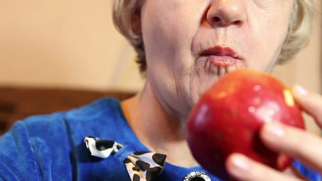 The woman is eating a ripe apple. Mouth and face close-up