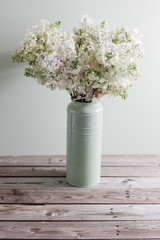 Lilac white Syringa flowers in vase. Spring background with white flowers in rustic Can on wooden table.