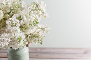 Lilac white Syringa flowers in vase. Spring background with white flowers in rustic Can on wooden table.