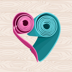 Two yoga mats stacked in the shape of heart on the wood floor. Pink and blue colors.
