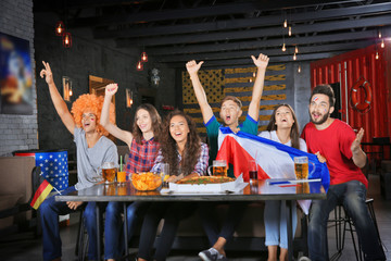 Cheerful friends watching soccer game in sport bar