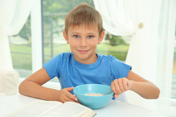 Little boy sitting at table with bowl of milk and cornflakes