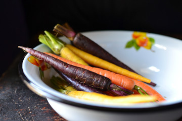 Fresh multicolored carrots in a white bowl